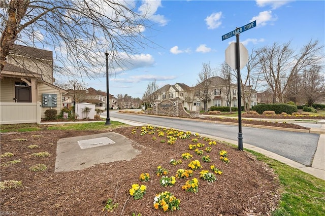 view of road featuring sidewalks, a residential view, street lighting, and traffic signs