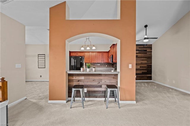 kitchen with a ceiling fan, stainless steel microwave, tasteful backsplash, freestanding refrigerator, and light colored carpet