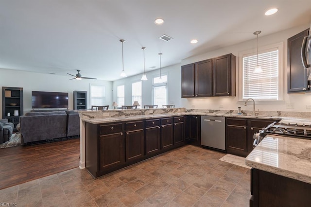 kitchen featuring a ceiling fan, open floor plan, stainless steel appliances, a peninsula, and dark brown cabinets