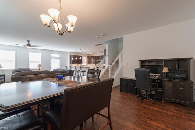 dining space featuring dark wood-style floors, stairs, and ceiling fan with notable chandelier