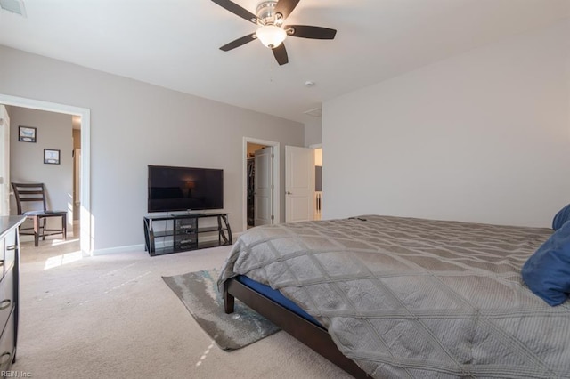 bedroom featuring a walk in closet, light colored carpet, visible vents, and ceiling fan