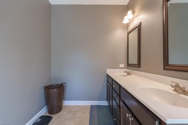 full bath with tile patterned flooring, double vanity, baseboards, and a sink