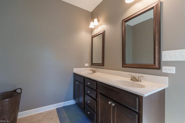 bathroom with a sink, baseboards, double vanity, and tile patterned floors