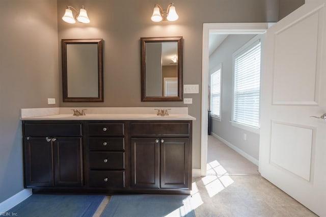 bathroom featuring a sink, baseboards, and double vanity