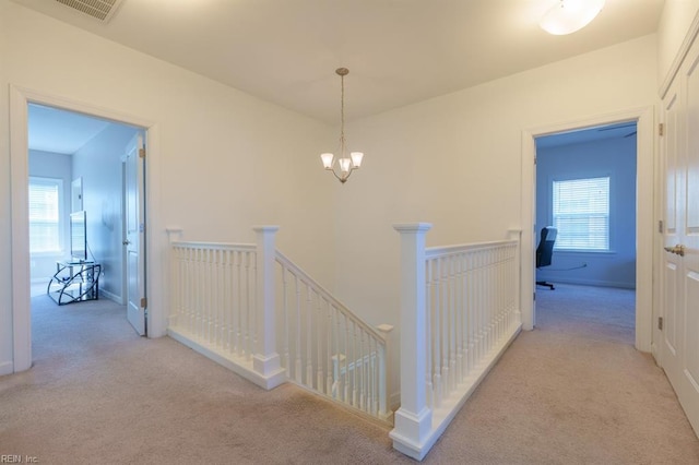 hall featuring carpet, an upstairs landing, and a wealth of natural light