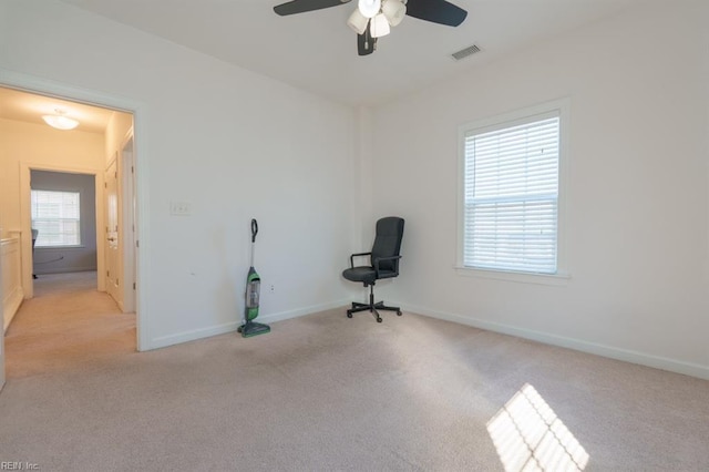 interior space with a ceiling fan, visible vents, light colored carpet, and baseboards