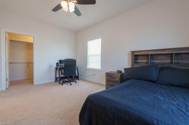 carpeted bedroom featuring a spacious closet, ceiling fan, and baseboards