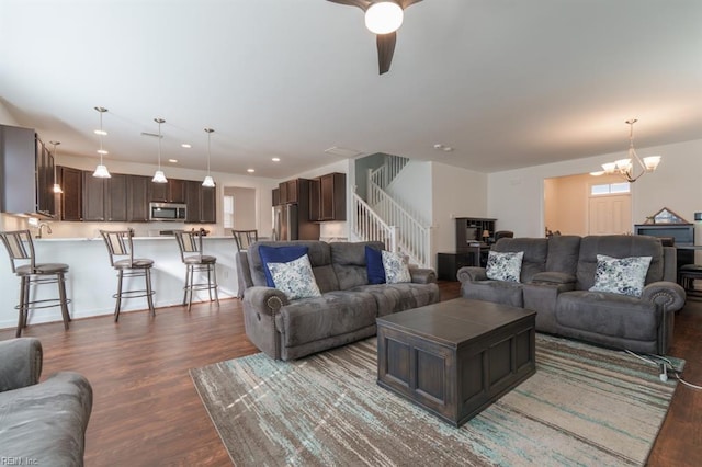 living room with recessed lighting, dark wood-type flooring, stairs, and ceiling fan with notable chandelier