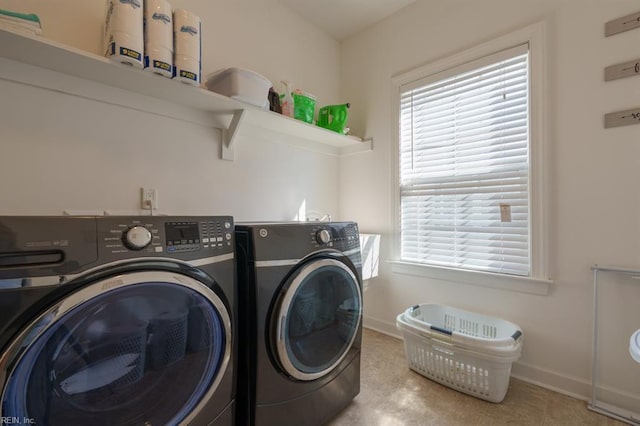 clothes washing area featuring washing machine and clothes dryer, laundry area, a healthy amount of sunlight, and baseboards