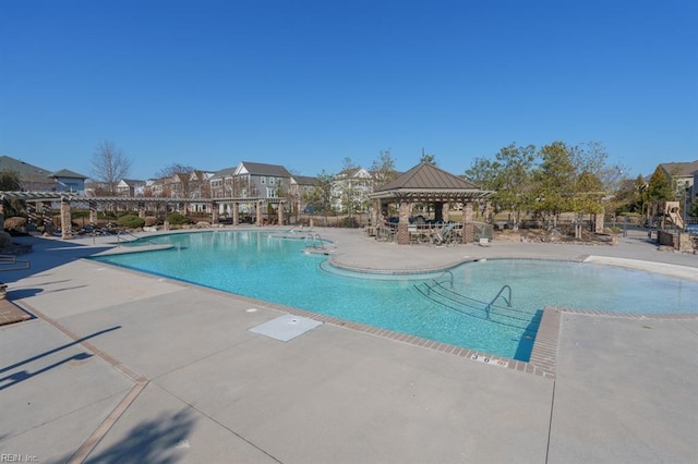 community pool with a gazebo and a patio