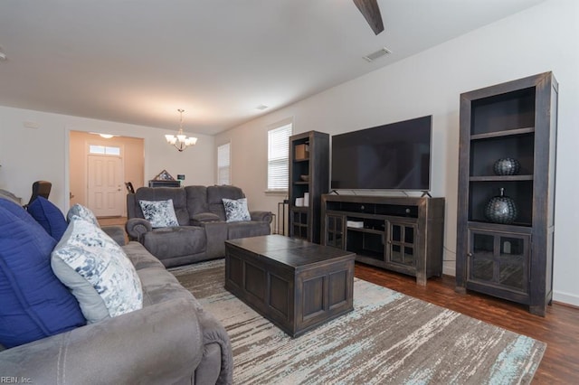 living room featuring visible vents, a notable chandelier, built in features, wood finished floors, and baseboards