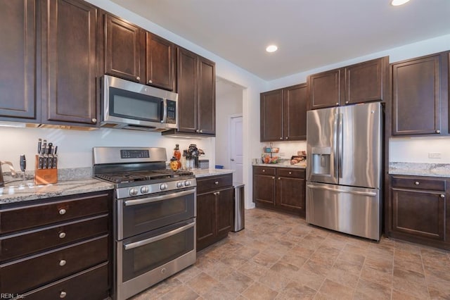 kitchen featuring recessed lighting, stainless steel appliances, light stone countertops, and dark brown cabinets