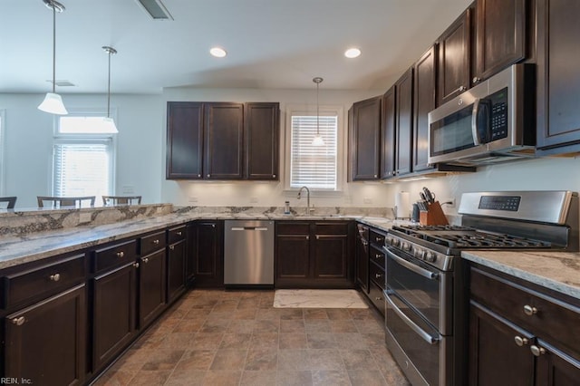 kitchen featuring hanging light fixtures, dark brown cabinetry, light stone counters, and stainless steel appliances