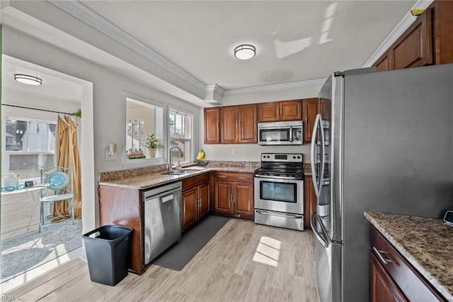 kitchen with light wood-type flooring, ornamental molding, a sink, appliances with stainless steel finishes, and light stone countertops