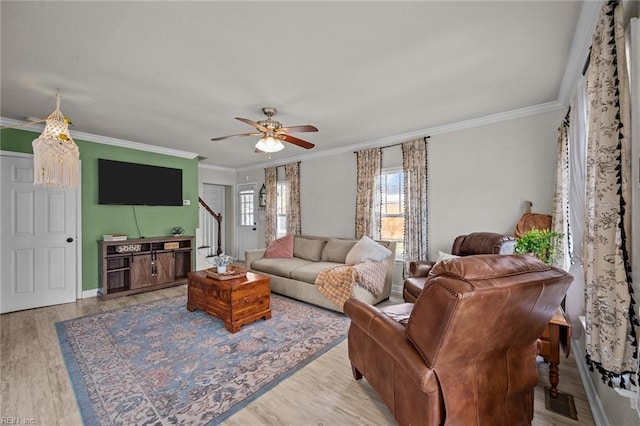 living room with ornamental molding, a ceiling fan, wood finished floors, stairway, and baseboards