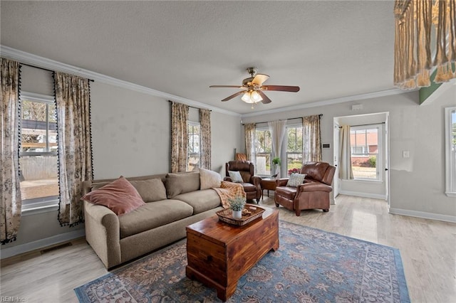 living area with crown molding, baseboards, light wood-style floors, a textured ceiling, and a ceiling fan