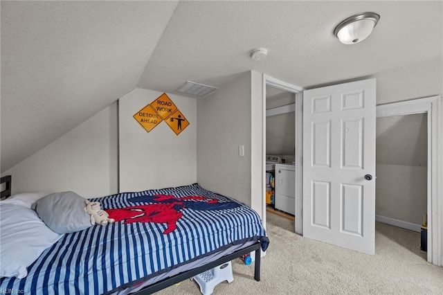 bedroom with carpet, visible vents, vaulted ceiling, a textured ceiling, and washing machine and dryer