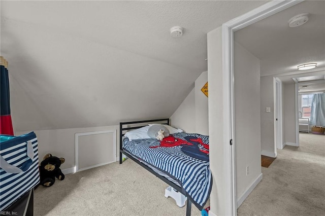 carpeted bedroom featuring attic access, a textured ceiling, baseboards, and vaulted ceiling