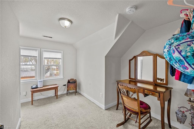 carpeted home office featuring baseboards, visible vents, a textured ceiling, and lofted ceiling