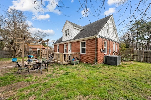 rear view of property with central air condition unit, brick siding, a fenced backyard, and an outdoor fire pit