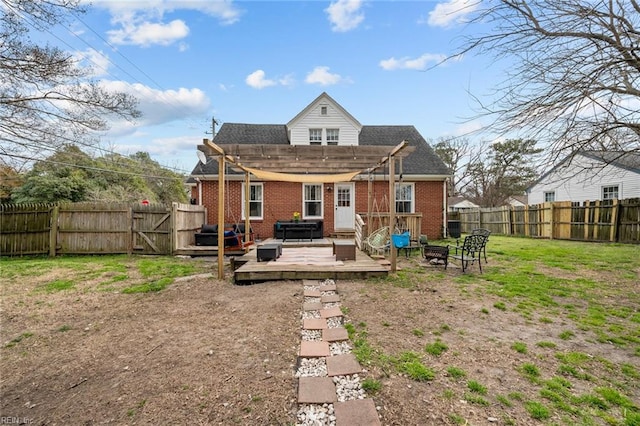 rear view of property featuring a deck, a fenced backyard, brick siding, and an outdoor fire pit