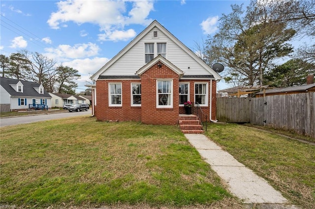 bungalow-style home with brick siding, a front yard, and fence