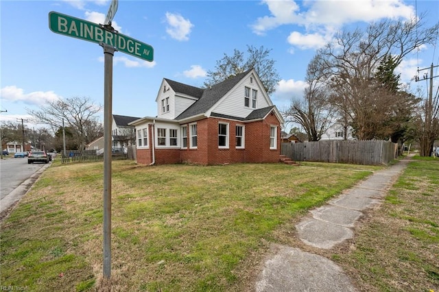 view of side of property with fence, brick siding, and a lawn