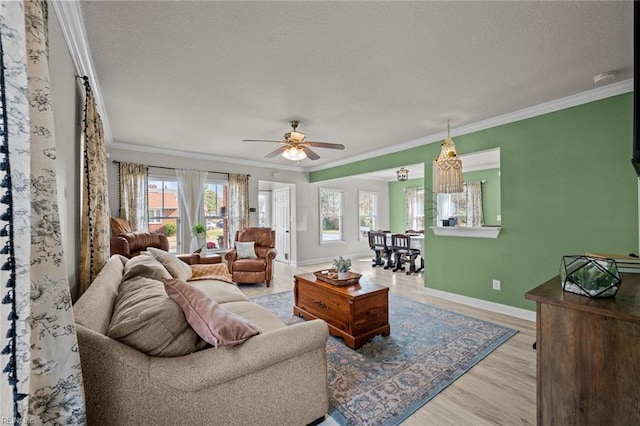 living room with light wood-style flooring, ornamental molding, a ceiling fan, a textured ceiling, and baseboards