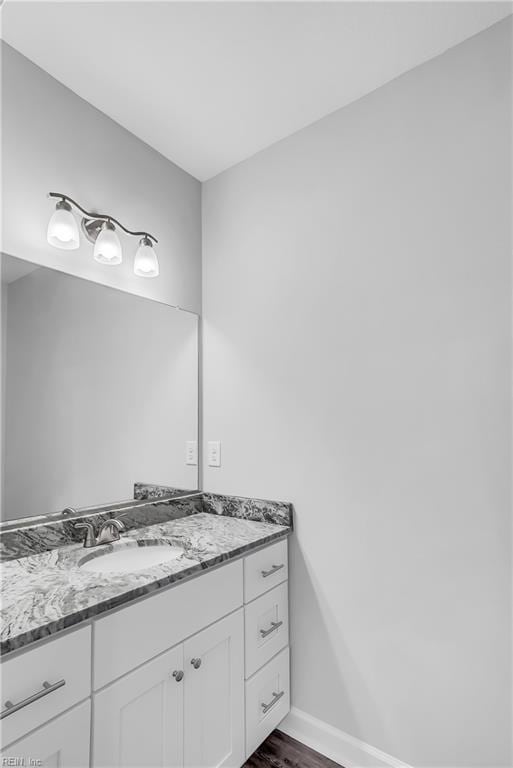 bathroom with baseboards, wood finished floors, and vanity