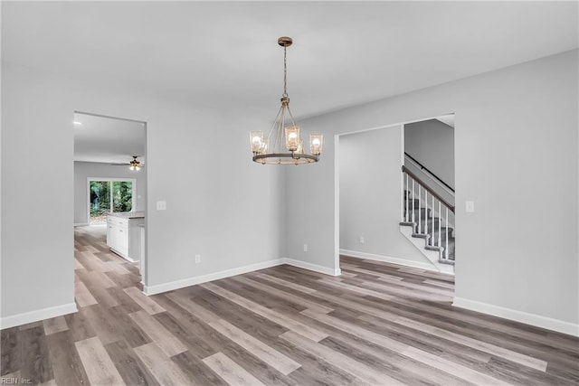 empty room featuring stairway, baseboards, and wood finished floors