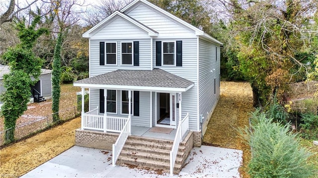 view of front of house featuring covered porch, a shingled roof, and fence