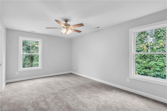 carpeted spare room with a ceiling fan, a healthy amount of sunlight, and baseboards