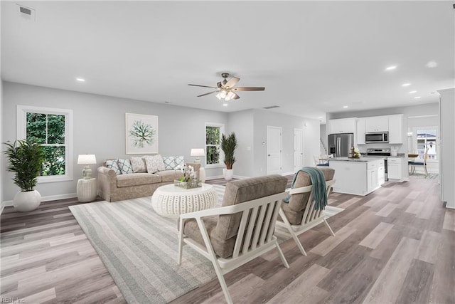 living area with baseboards, visible vents, recessed lighting, ceiling fan, and light wood-type flooring