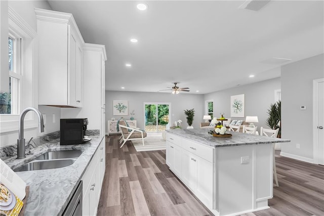 kitchen with white cabinetry, a center island, recessed lighting, and a sink