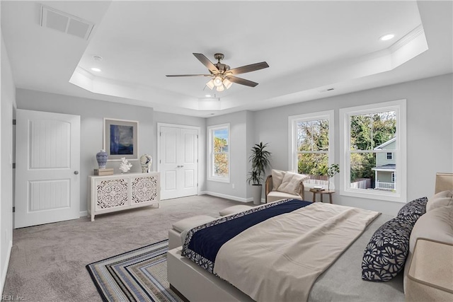 carpeted bedroom with a raised ceiling, recessed lighting, baseboards, and visible vents