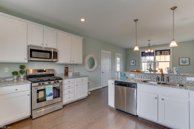 kitchen featuring a sink, appliances with stainless steel finishes, hanging light fixtures, white cabinetry, and dark wood-style flooring