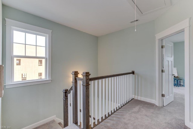 hall with an upstairs landing, visible vents, attic access, and carpet