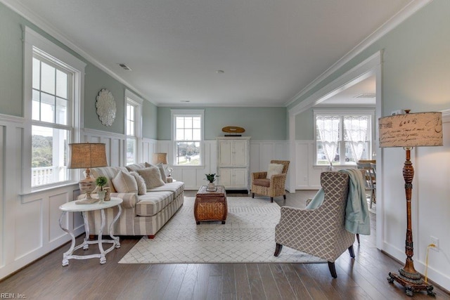 living room with visible vents, ornamental molding, a wainscoted wall, and wood-type flooring