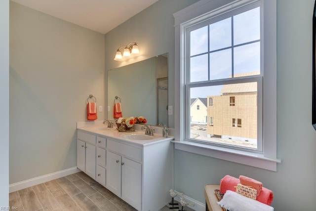 bathroom featuring a sink, baseboards, wood finished floors, and double vanity