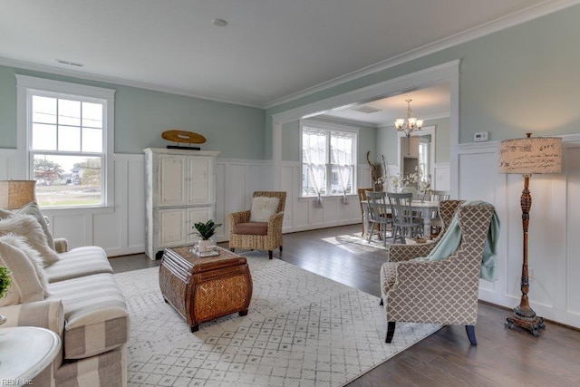 living area with a wainscoted wall, wood finished floors, a chandelier, and ornamental molding