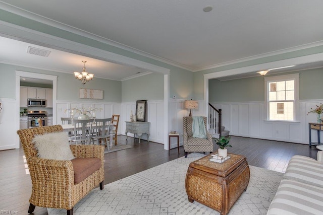 living area with visible vents, an inviting chandelier, stairs, wood-type flooring, and wainscoting