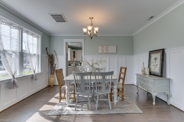 dining area with visible vents, an inviting chandelier, wood finished floors, and crown molding