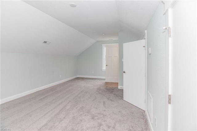 additional living space with carpet flooring, visible vents, baseboards, and lofted ceiling