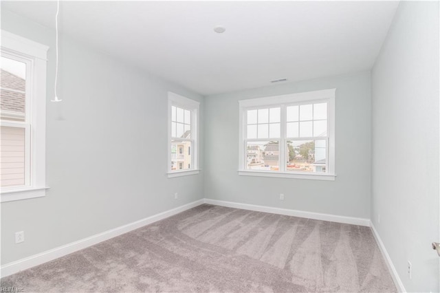 empty room featuring visible vents, a healthy amount of sunlight, baseboards, and carpet floors