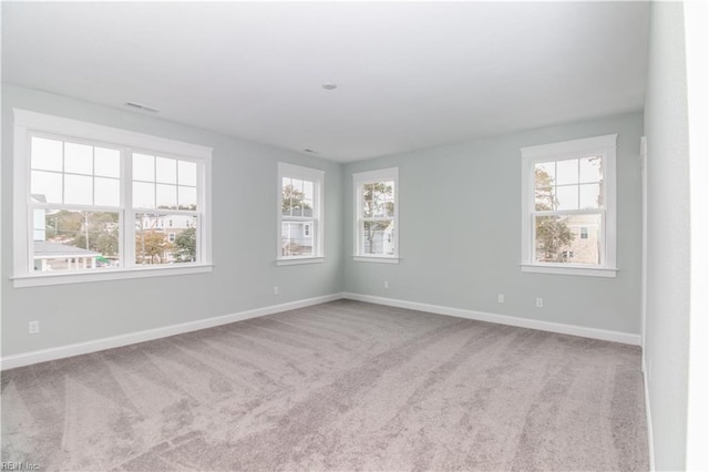 carpeted empty room featuring visible vents and baseboards