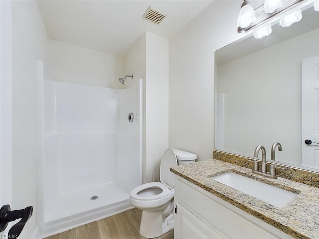 full bathroom featuring visible vents, toilet, wood finished floors, vanity, and a shower