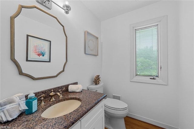 bathroom featuring vanity, wood finished floors, baseboards, visible vents, and toilet