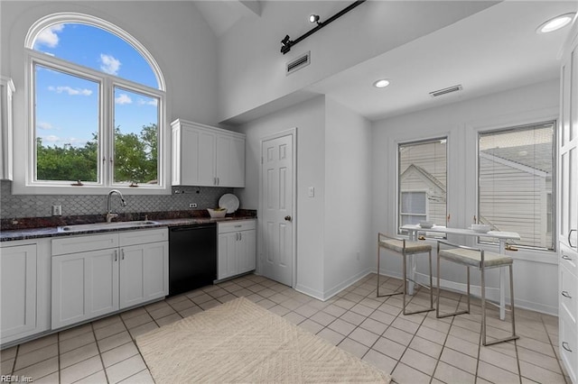 kitchen featuring visible vents, a sink, tasteful backsplash, light tile patterned flooring, and dishwasher