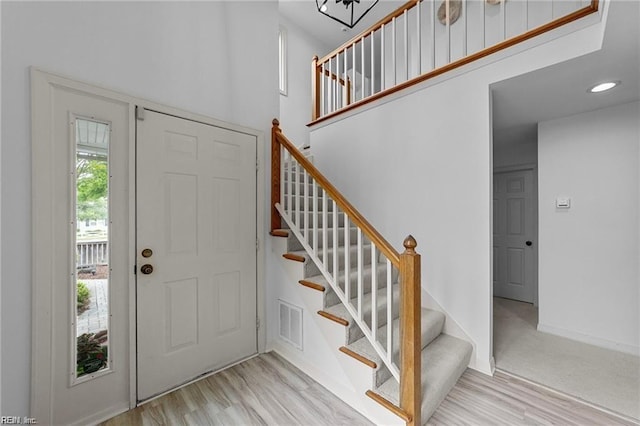 entrance foyer with visible vents, stairway, baseboards, and wood finished floors