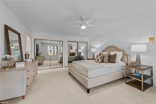 bedroom featuring multiple closets, light colored carpet, and a ceiling fan